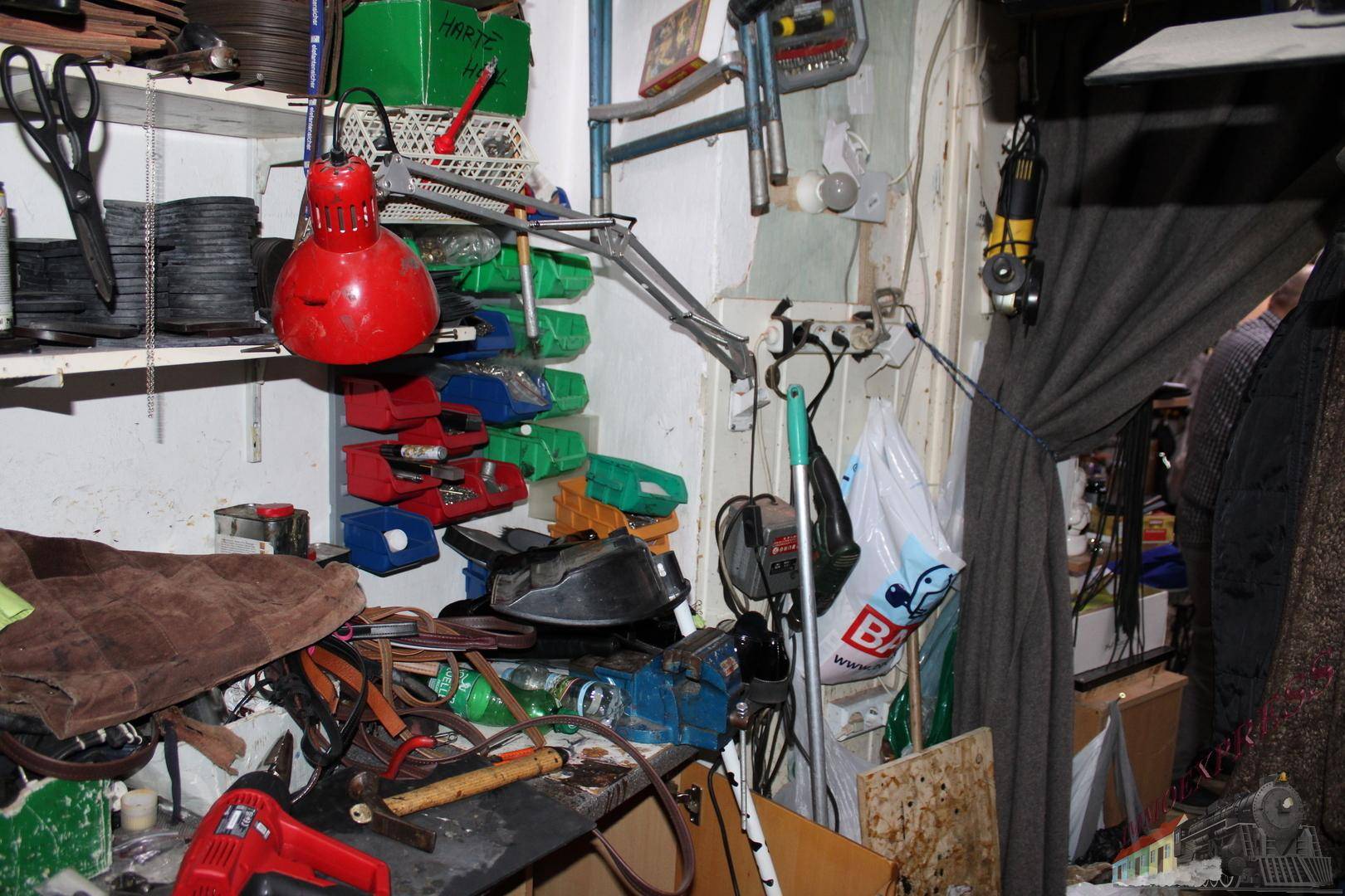 Unordentlicher Werkstattbereich mit Werkzeugen, Materialien und einer roten Lampe an der Wand montiert.