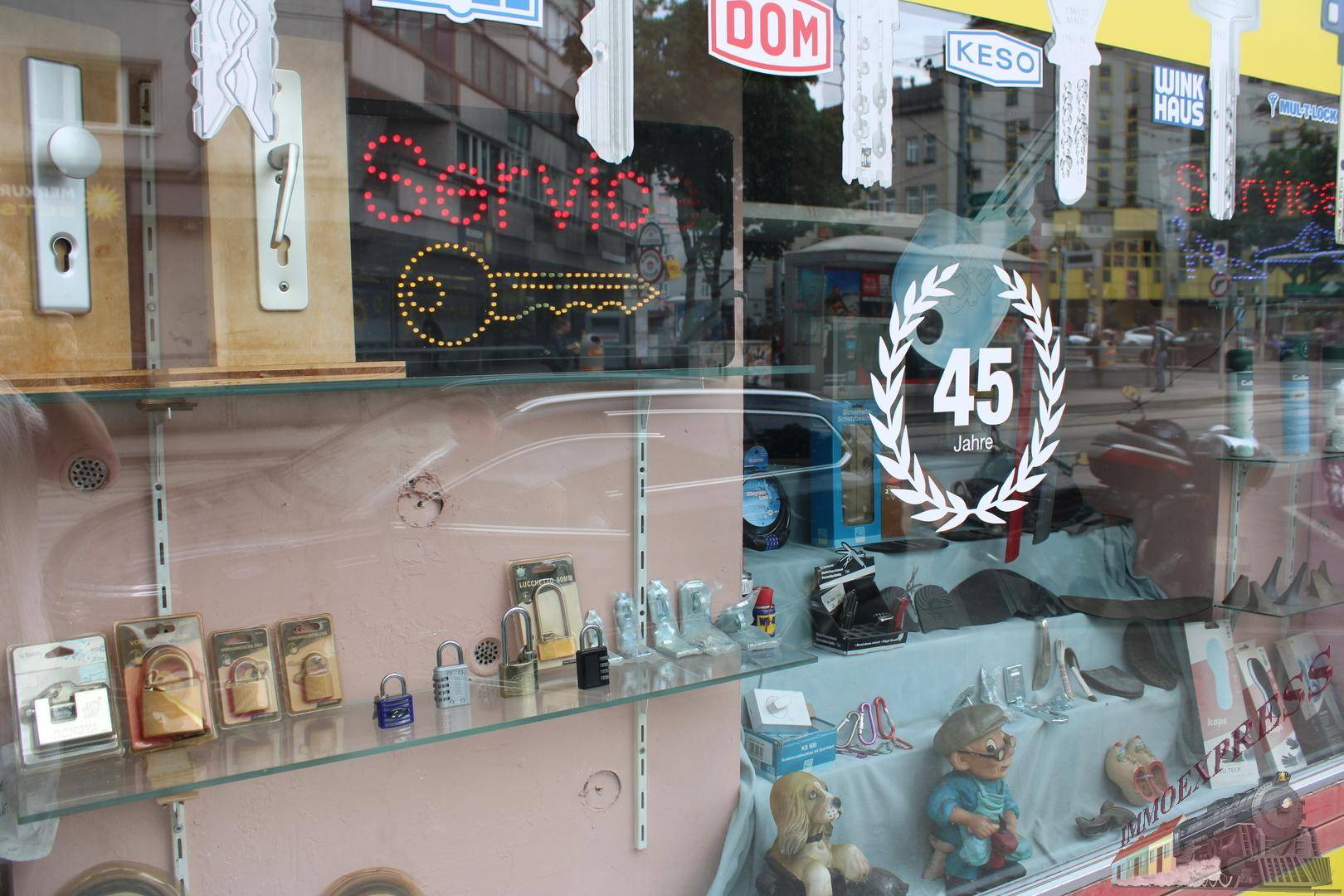 Schaufenster eines Geschäfts mit Schlüssel- und Schlossprodukten sowie einer leuchtenden "Service"-Reklame.