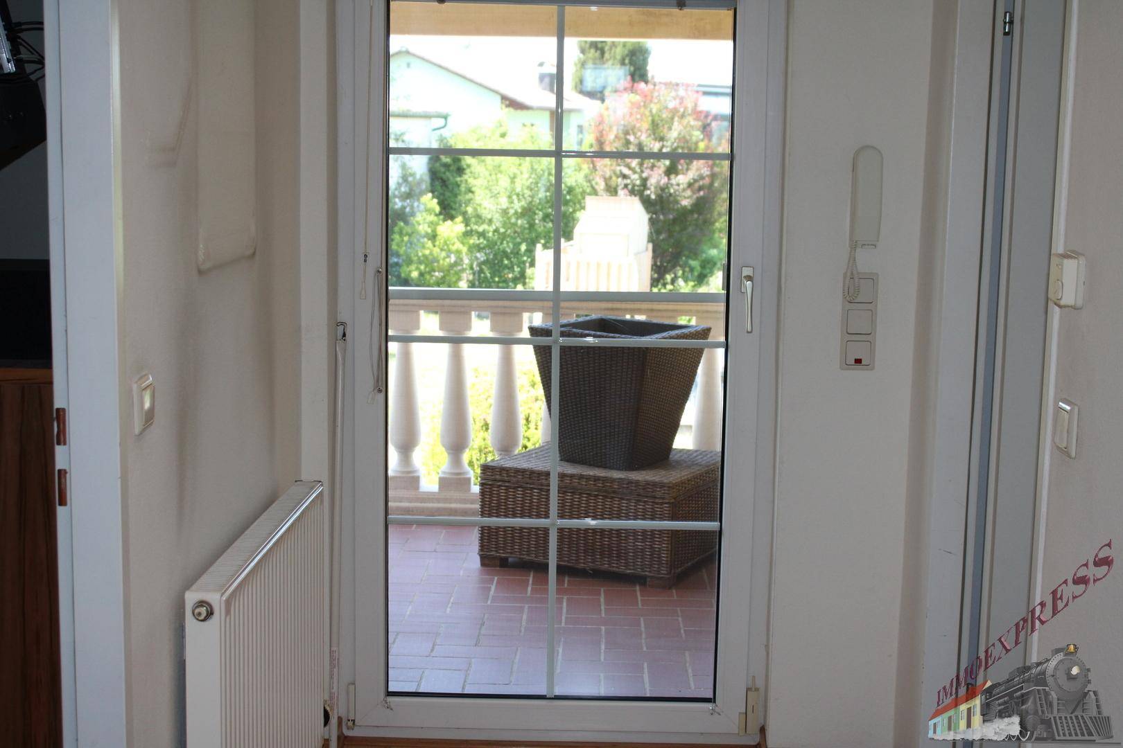 Heller Flur mit Tür, die zu einem Außenbereich mit Balustrade führt.
