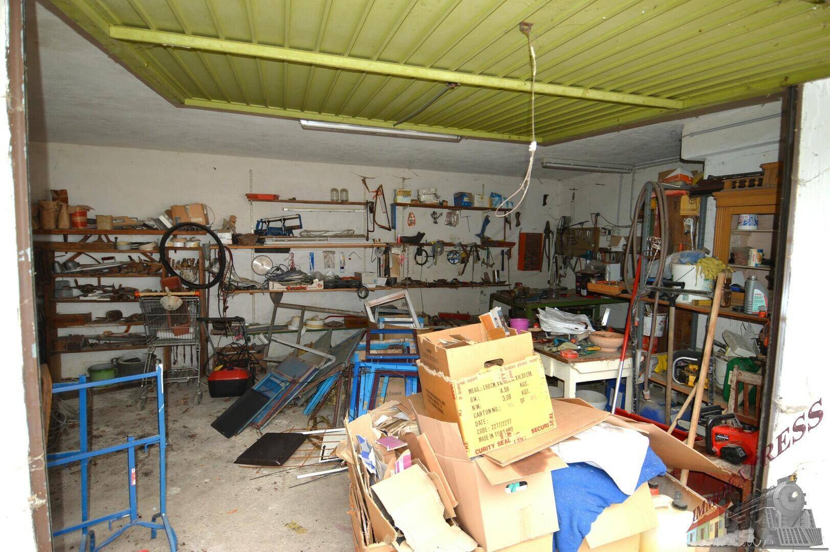 Unaufgeräumte Garage oder Werkstatt mit vielen Werkzeugen, Regalen und Kartons.