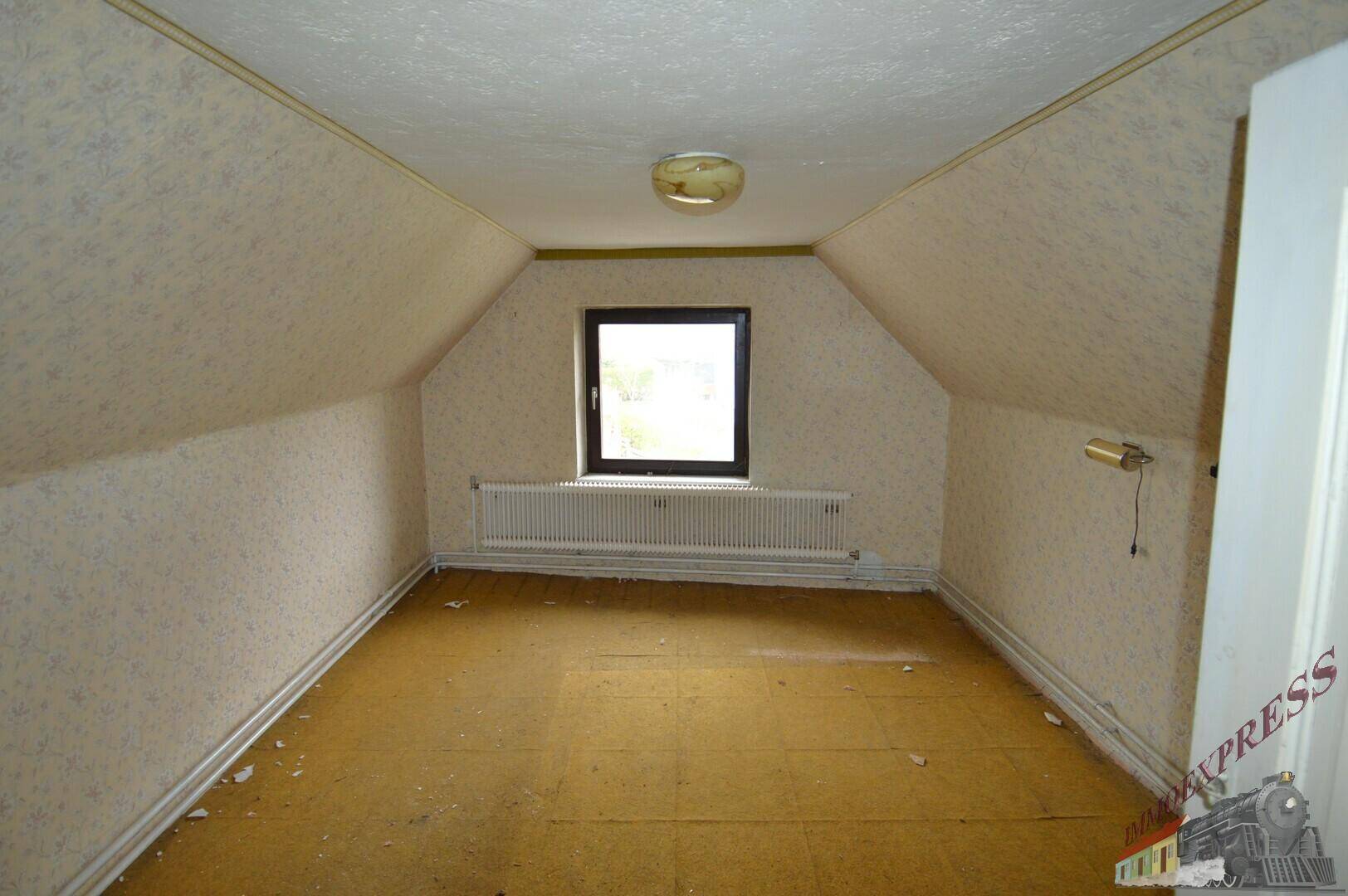 Dachzimmer mit schrägen Wänden, kleinem Fenster und Teppichboden, ideal als Schlafzimmer.