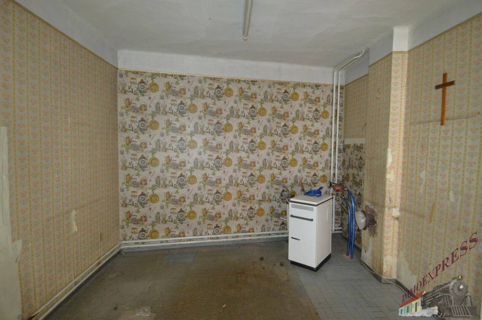 Raum mit gemusterter Tapete und einem Heizkessel, der als Hauswirtschaftsraum dienen könnte.