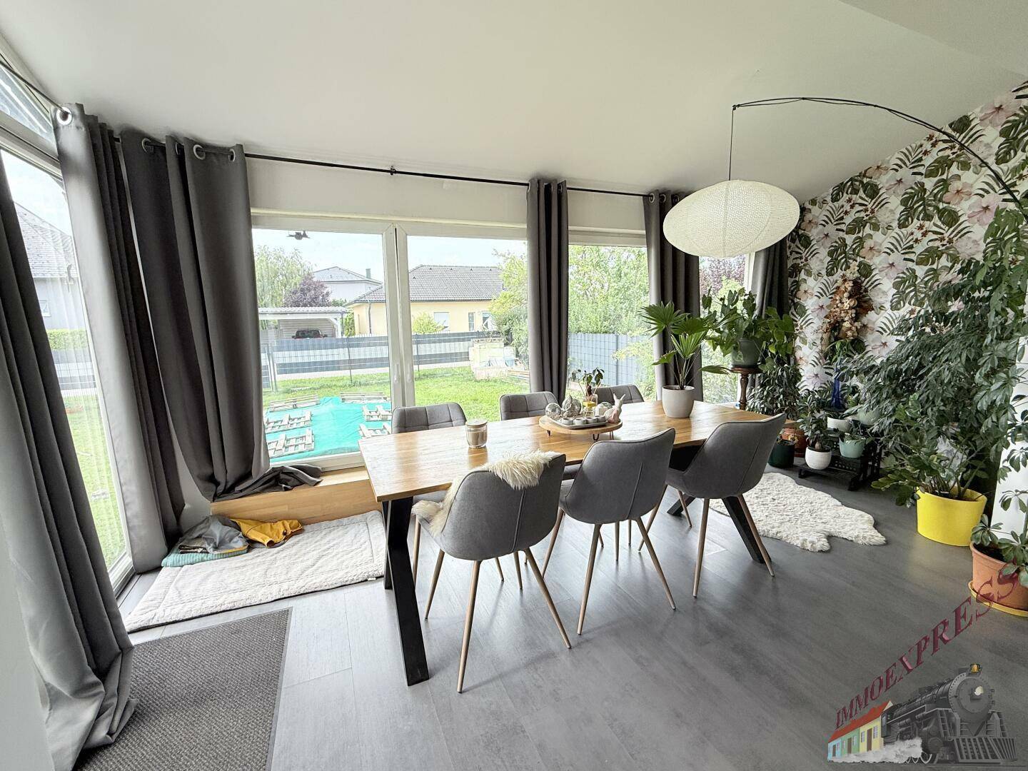 Heller Essbereich mit Holztisch, modernen Stühlen und großen Fenstern zum Garten.