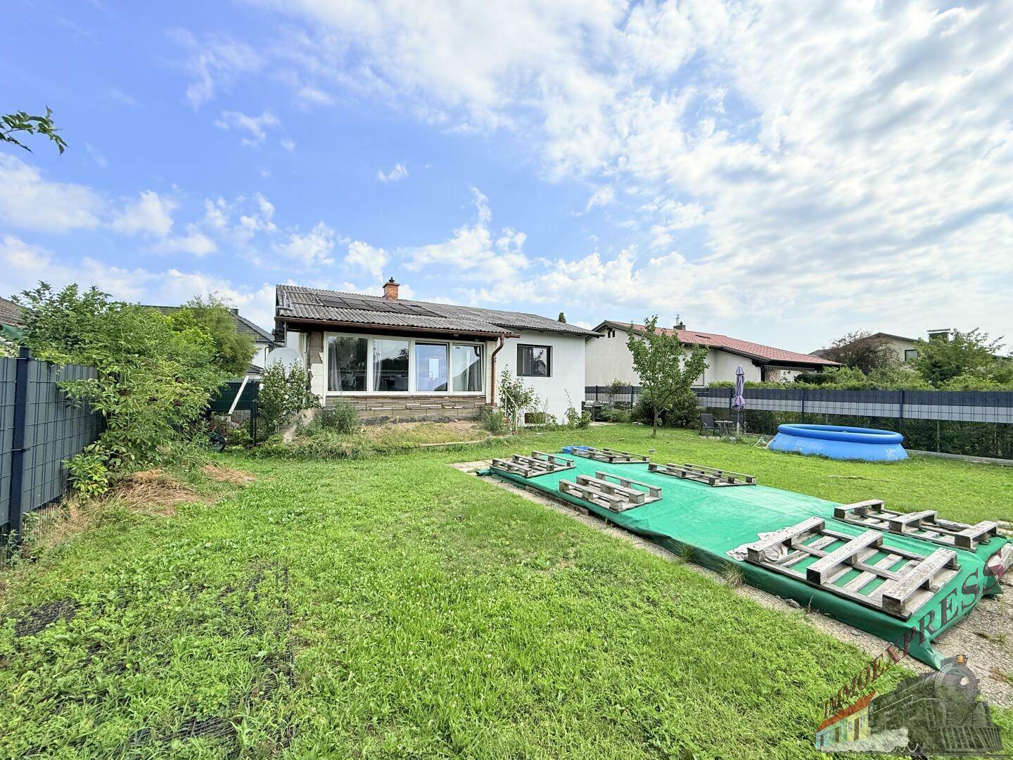 Großer Gartenbereich hinter dem Haus mit Rasenfläche, vorbereitetem Beet und kleinem Pool.
