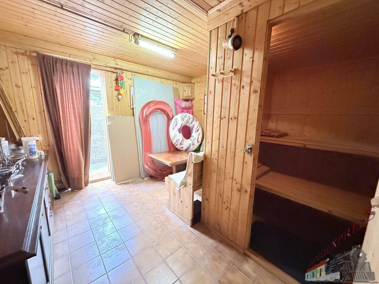 Raum mit integrierter Sauna, gefliestem Boden und Zugang zum Außenbereich.