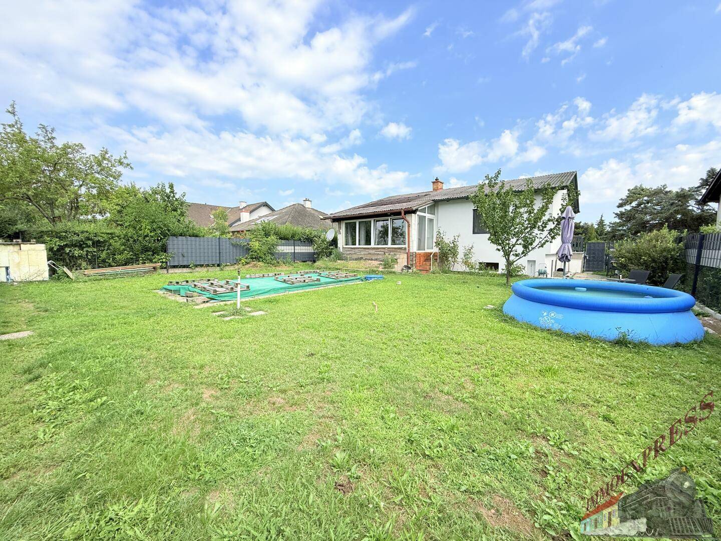 Weitläufiger Garten mit viel Rasenfläche, einem aufblasbaren Pool und Blick auf die Umgebung.