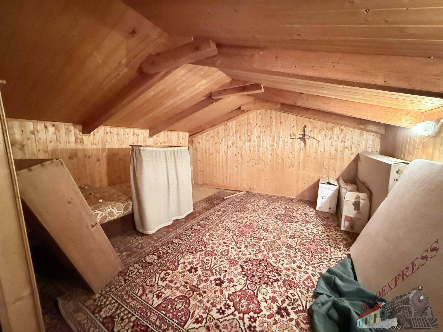 Weiterer Bereich des Dachbodens mit Teppichboden und zusätzlichen Abstellmöglichkeiten.