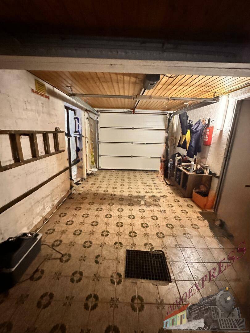Geräumige Garage mit Rolltor, gefliestem Boden und Platz für ein Fahrzeug.