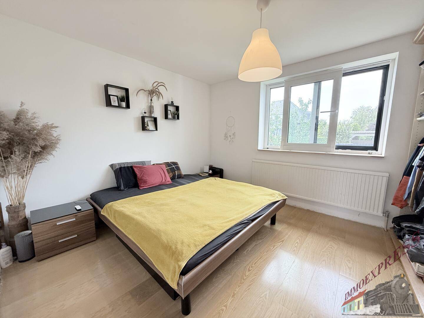 Helles Schlafzimmer mit Doppelbett, Nachttischen und großem Fenster.