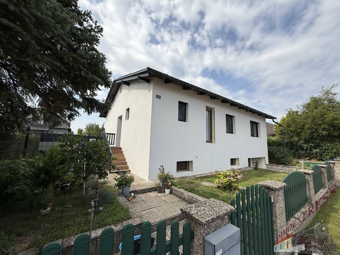 Gut erhaltenes Einfamilienhaus mit weißer Fassade, Satteldach und kleinem Vorgarten.