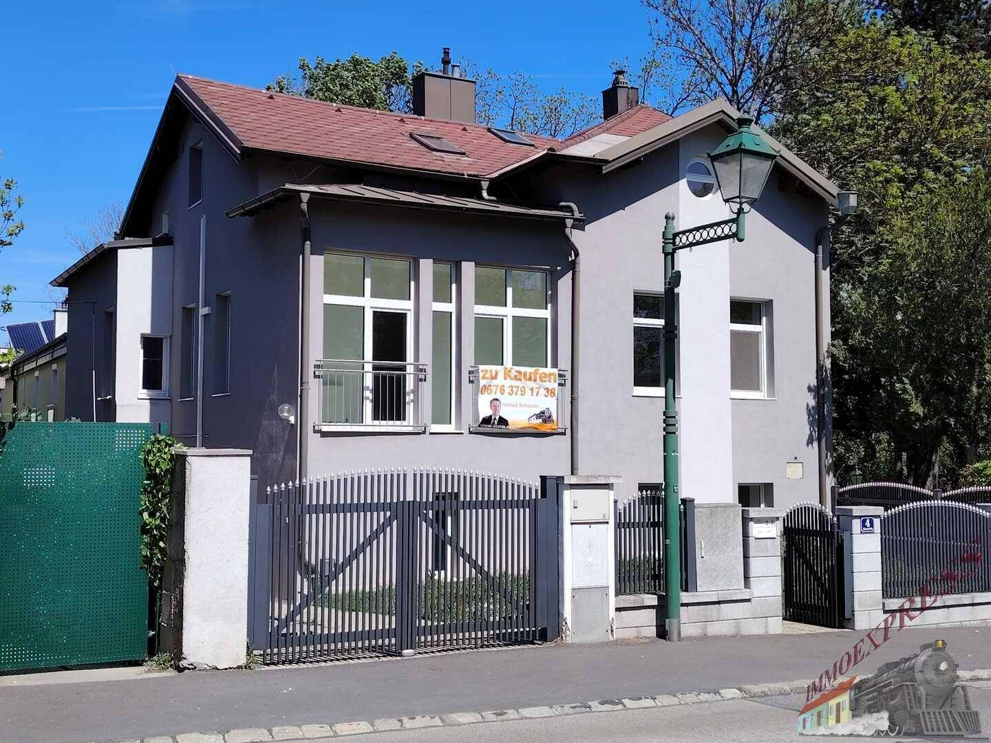 Seitenansicht des Hauses mit Eingangstor, Zaun und einer klassischen Straßenlaterne.