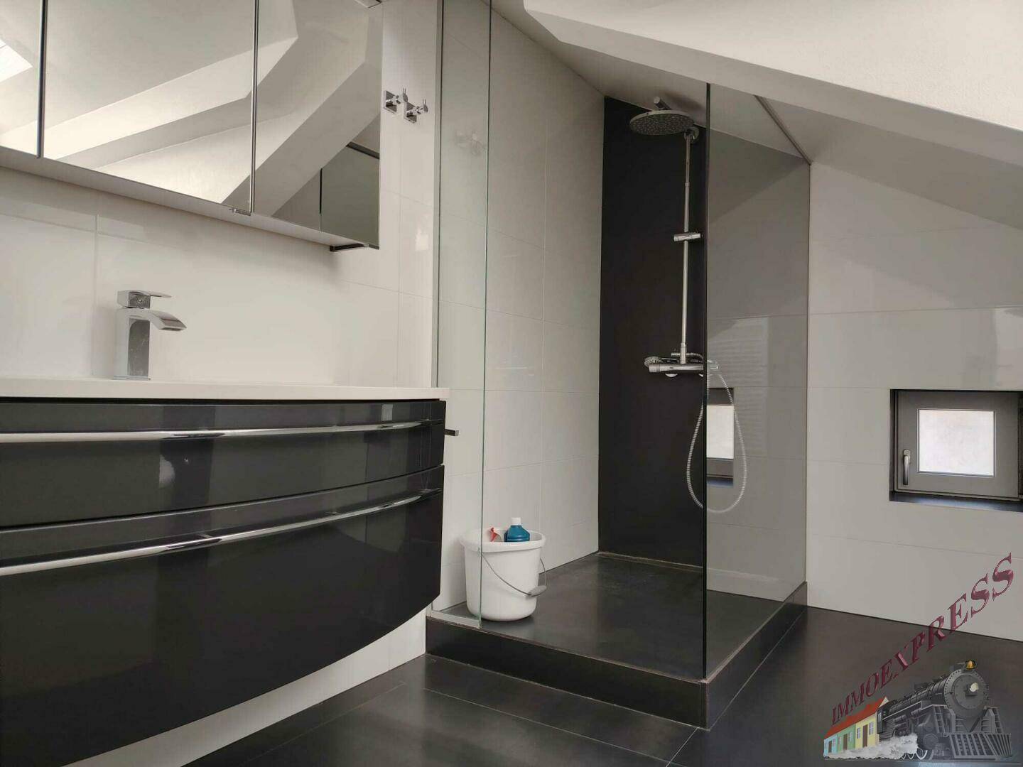 Modernes Dachgeschossbad mit begehbarer Dusche, dunklem Waschtisch und kleinem Fenster.