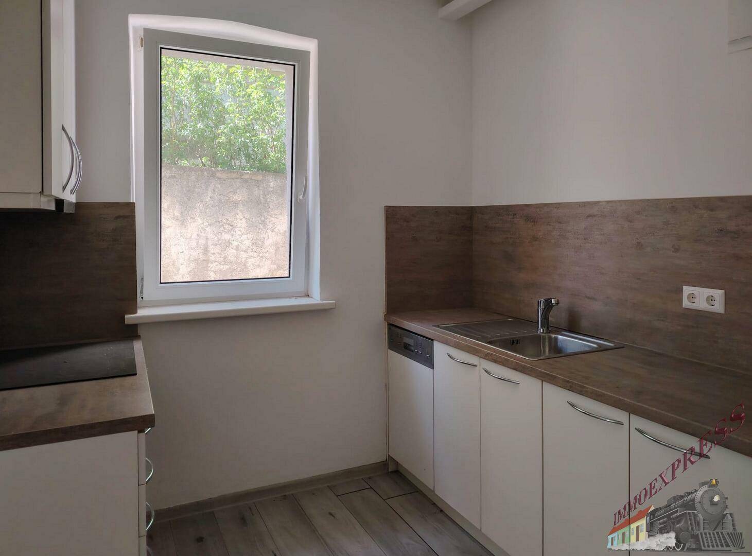 Kleine Küche mit weißen Schränken, Holzoptik-Arbeitsplatte und integrierten Geräten.