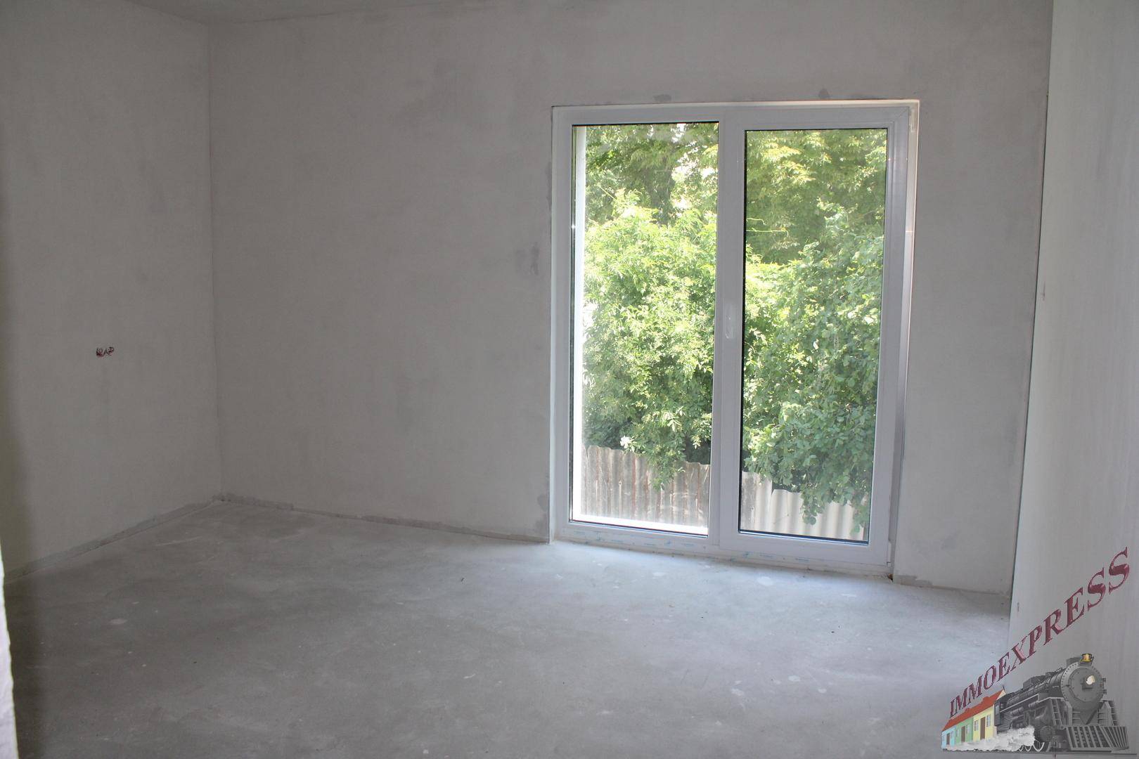 Helles, unfertiges Zimmer mit großem Fenster und Blick auf die umliegende Vegetation.