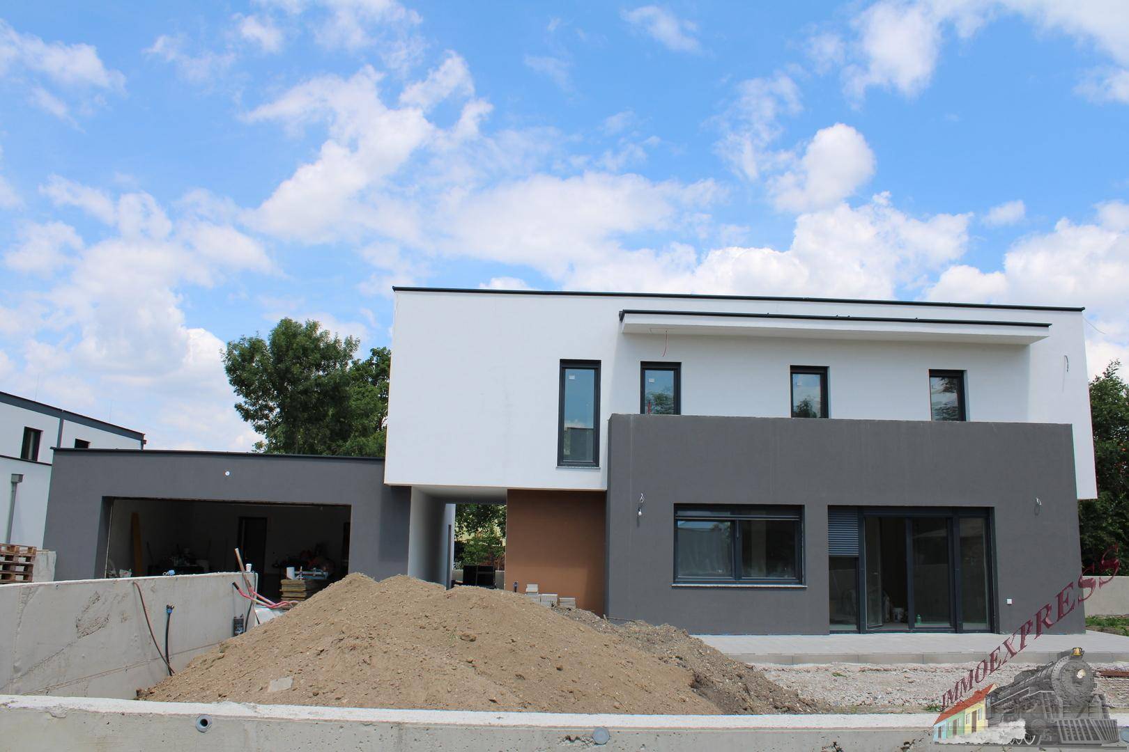 Neubau-Doppelhaushälfte mit moderner Architektur, großen Fenstern und Baustellenbereich im Vordergrund.