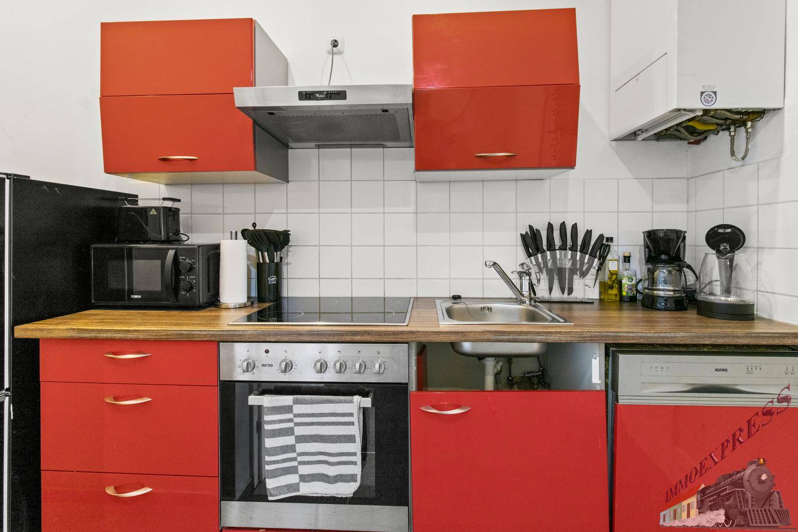 Moderne Küche mit roten Hochglanzfronten, integrierten Geräten und einer robusten Holz-Arbeitsplatte.