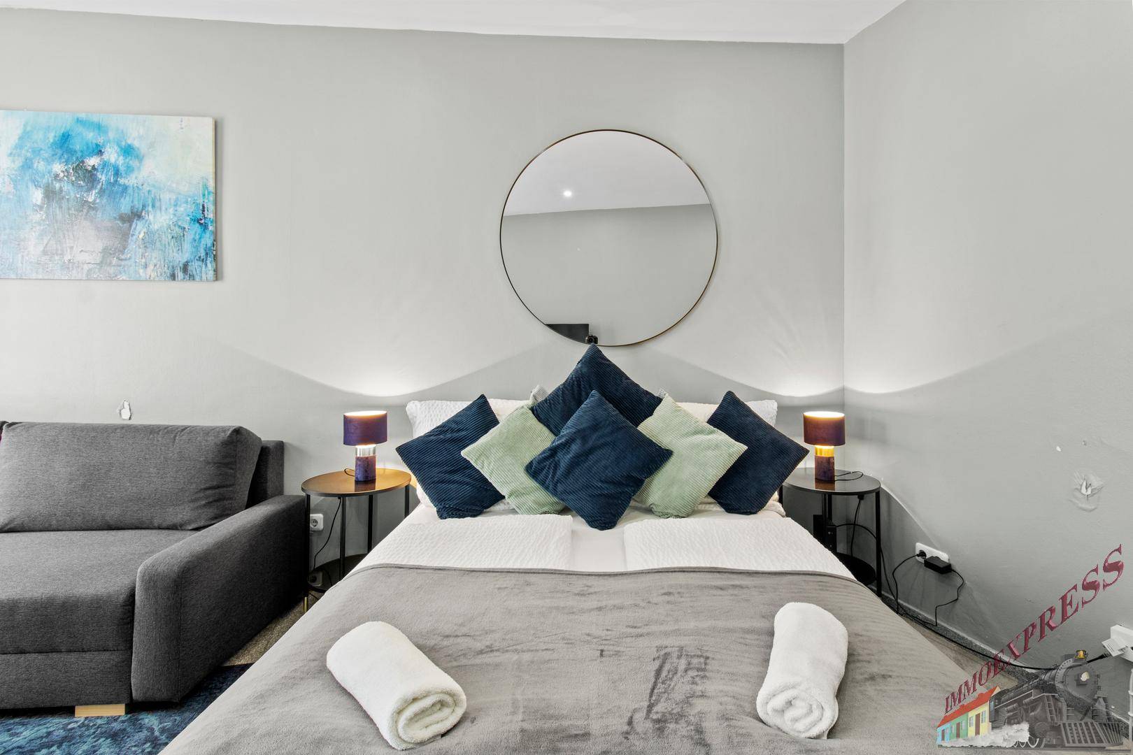Gemütliches Schlafzimmer mit Doppelbett, blauen Kissen und einem modernen Kunstwerk über dem Bett.