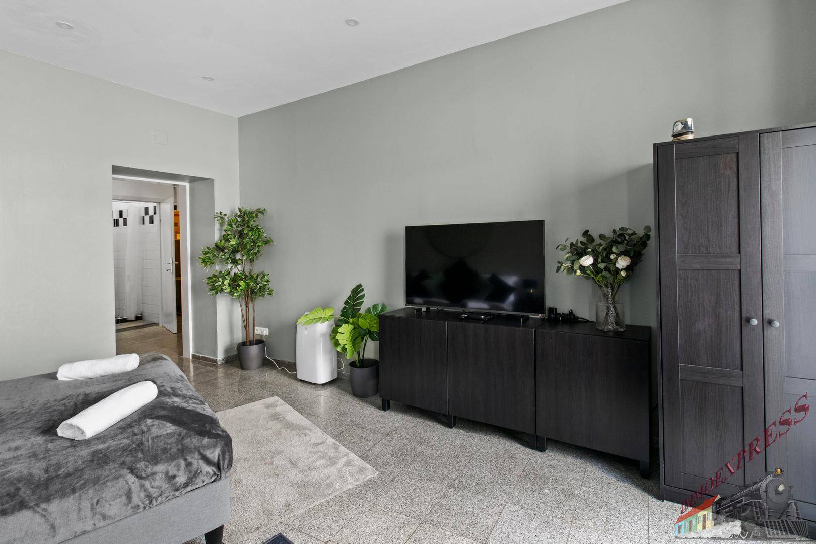 Schlafzimmer mit Fernseher auf einem Sideboard und einem Kleiderschrank, der zusätzlichen Stauraum bietet.