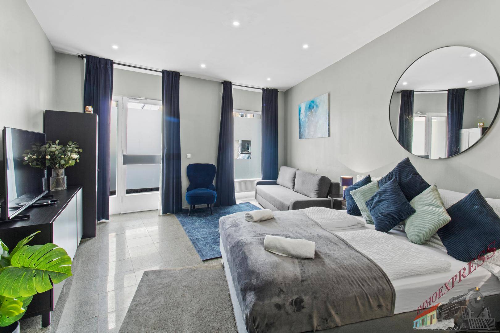 Geräumiges Schlafzimmer mit Doppelbett, Schlafsofa und Zugang zu einem Außenbereich durch große Fenster.