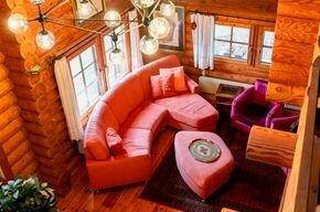 Gemütliches Wohnzimmer mit Holzvertäfelung, rotem Sofa und dekorativer Beleuchtung.