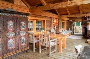 Rustikale Loggia mit Holzbalken, Esstisch und einem traditionellen bemalten Schrank.