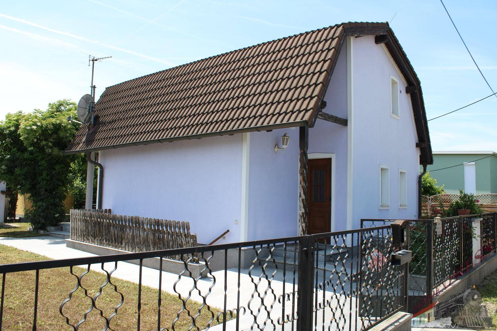 Seitenansicht des Hauses mit Eingangsbereich und dekorativem Zaun.