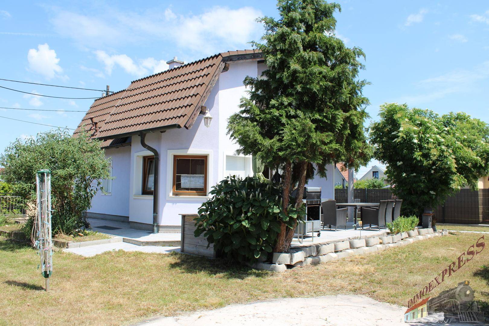 Seitenansicht des Hauses mit gepflegtem Rasen und Zugang zur Terrasse.