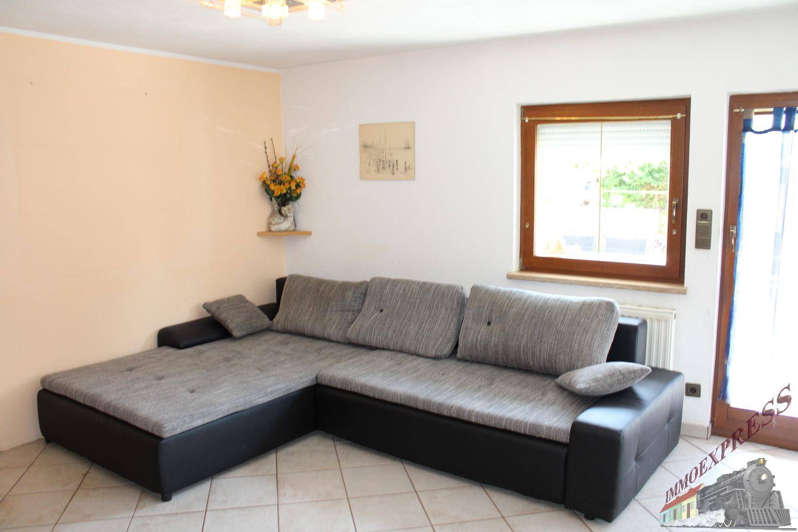 Helles Wohnzimmer mit bequemer Eckcouch und Fliesenboden, ideal zum Entspannen.