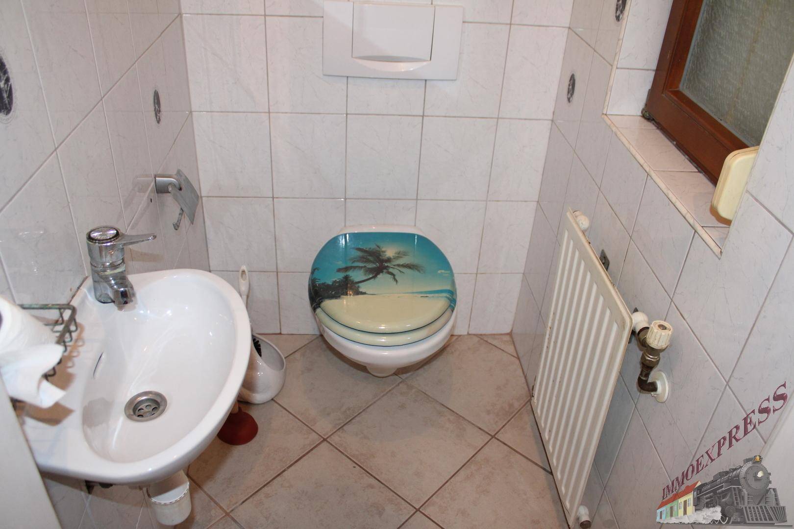 Kleines Gäste-WC mit Waschbecken, Toilette und Fenster für natürliche Belüftung.