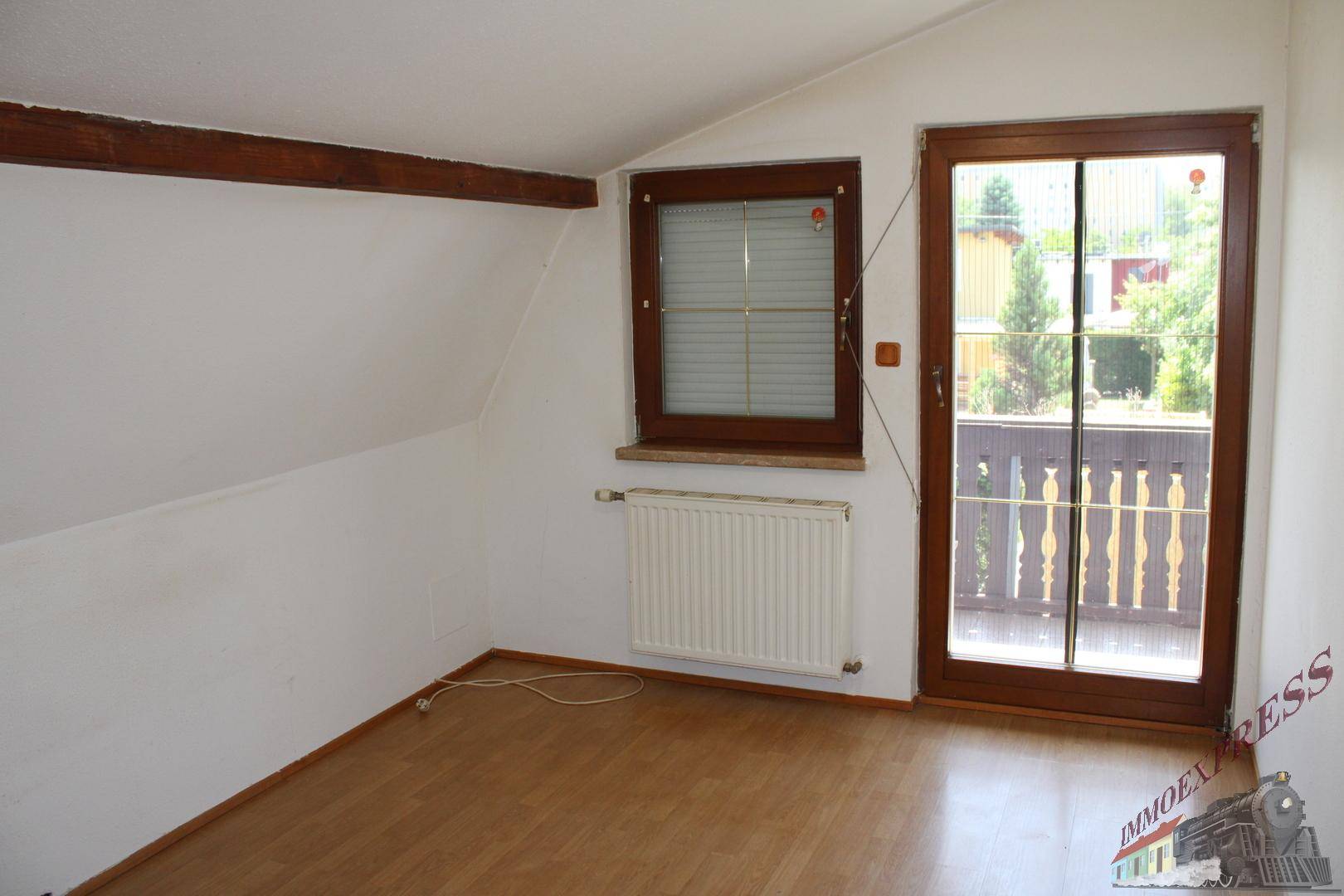 Helles Schlafzimmer mit Laminatboden und direktem Zugang zu einem charmanten Balkon.