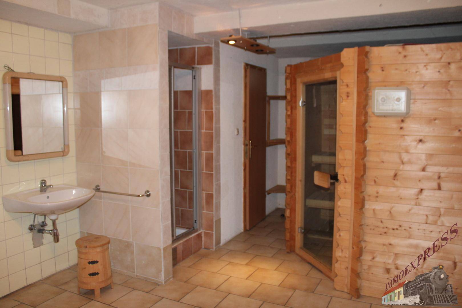 Badezimmer im Untergeschoss mit Dusche, Waschbecken und direktem Zugang zur Sauna.