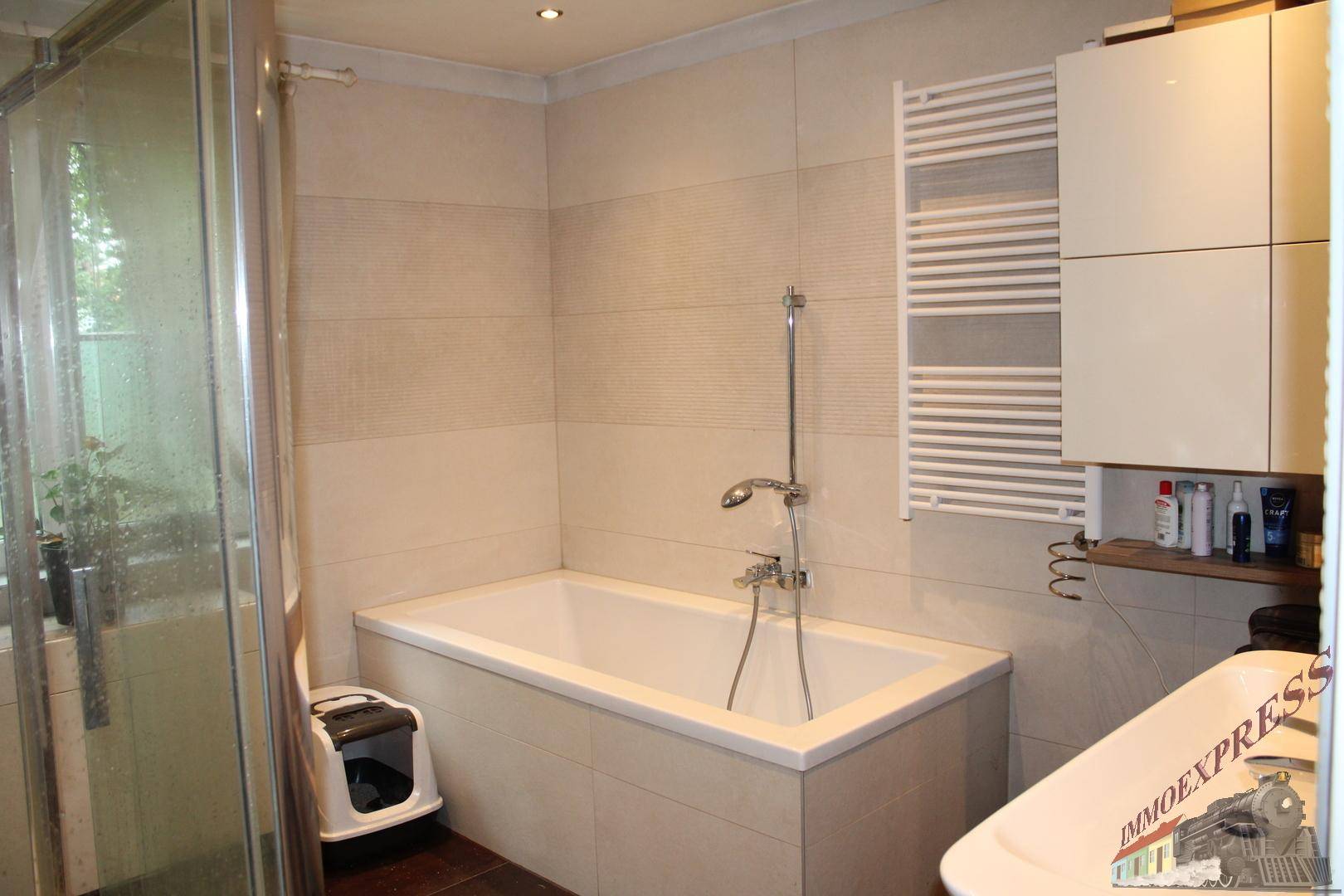 Modernes Badezimmer mit Badewanne, Duschkabine und beheiztem Handtuchhalter.