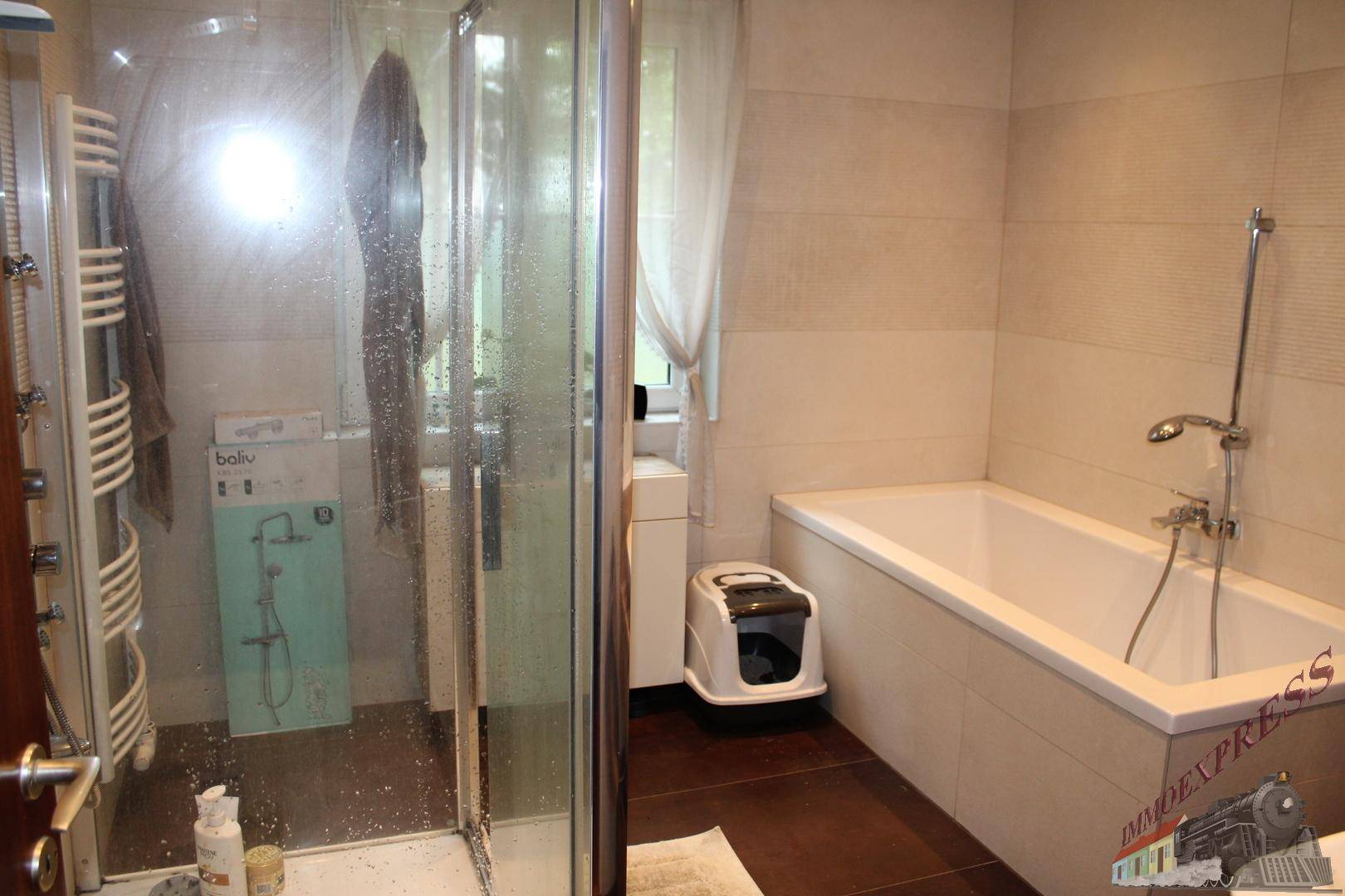 Badezimmer mit Badewanne und Duschkabine, hell gefliest und mit Fenster.