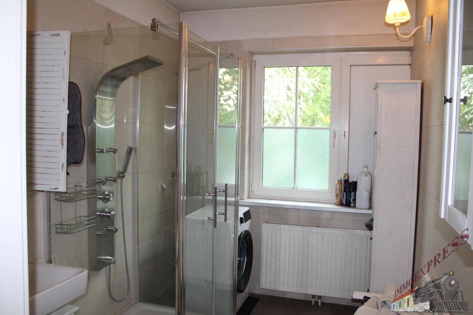 Badezimmer mit Duschkabine, Waschmaschine und Fenster, hell und funktional.
