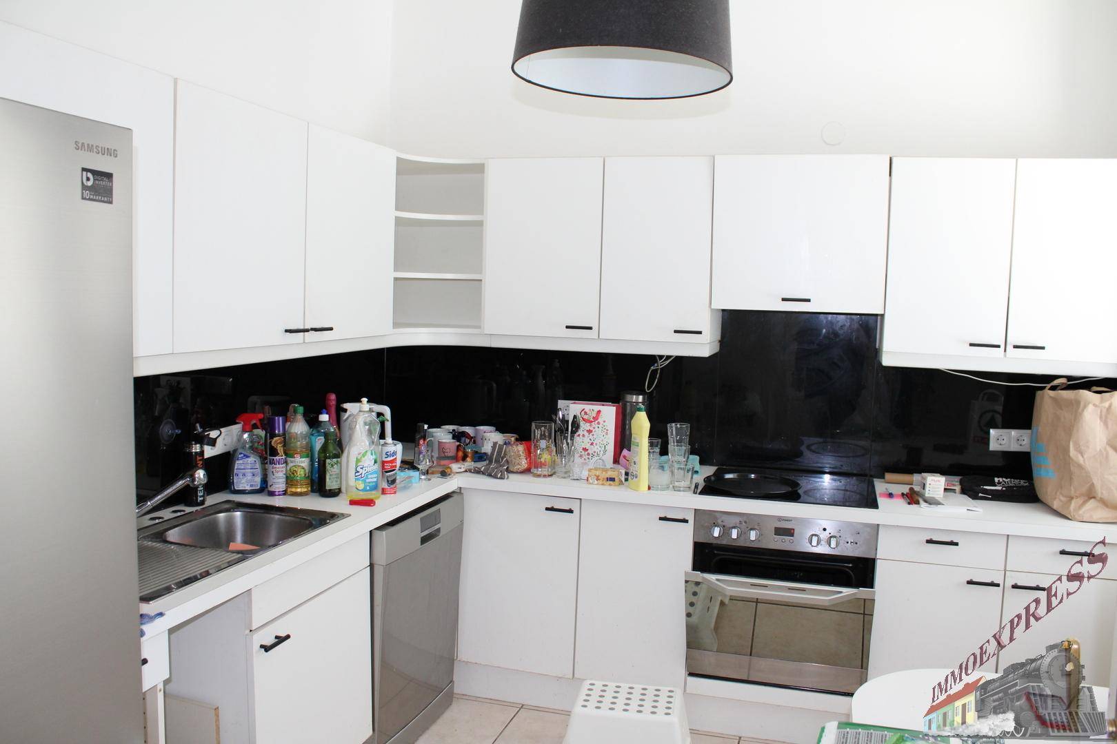Moderne Küche mit weißen Schränken, schwarzer Rückwand und integrierten Edelstahlgeräten.