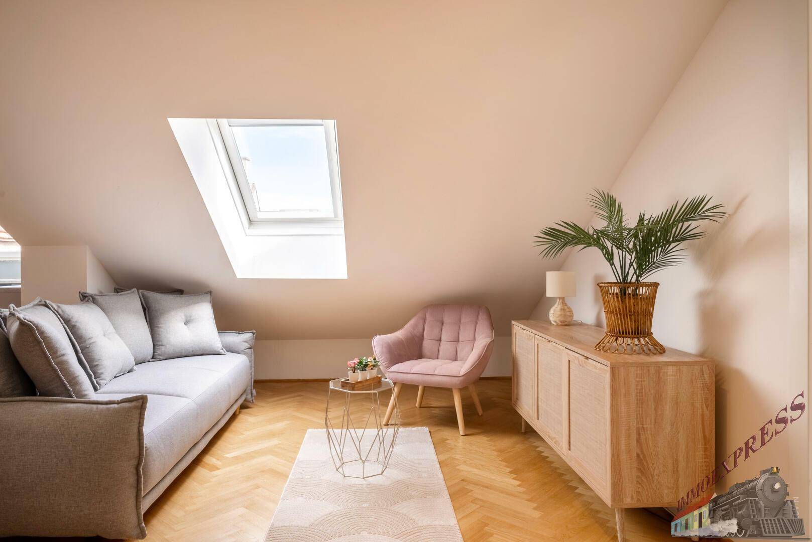 Heller Wohnbereich unter Dachschrägen mit Dachfenster, Sofa und stilvollen Möbeln.