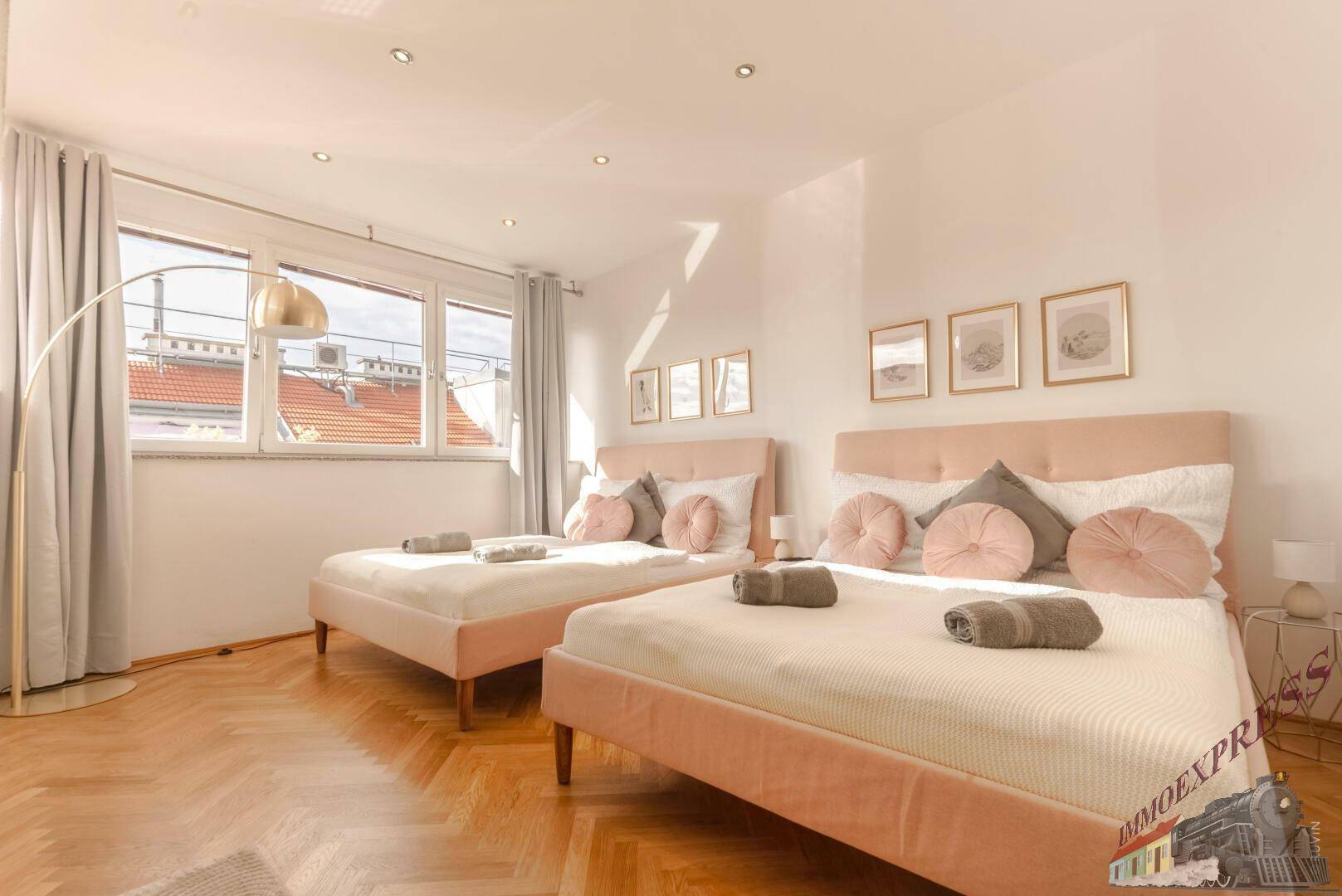 Geräumiges Schlafzimmer mit zwei Betten, großen Fenstern und Fischgrätparkett.