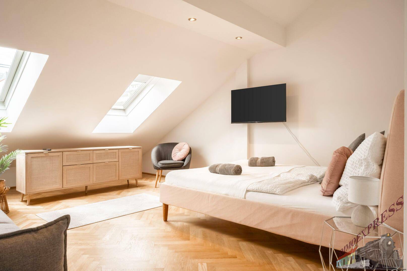Helles Schlafzimmer mit Dachschrägen, zwei Dachfenstern und modernem Bett.