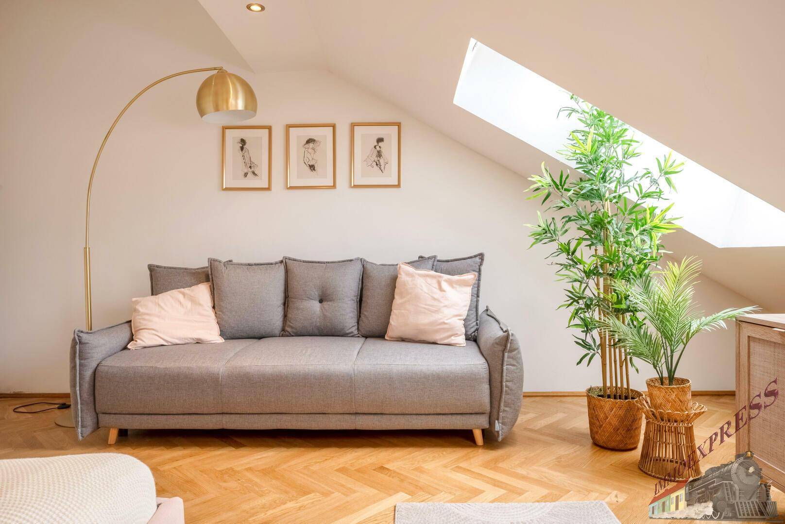 Gemütlicher Wohnbereich unter Dachschrägen mit Sofa, Pflanzen und Dachfenster.