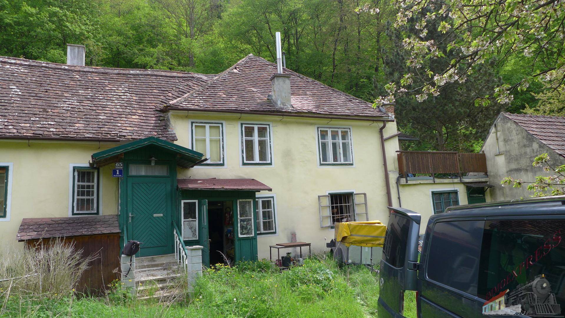 Vorderansicht eines ländlichen Hauses mit grüner Eingangstür und einem geparkten Lieferwagen.