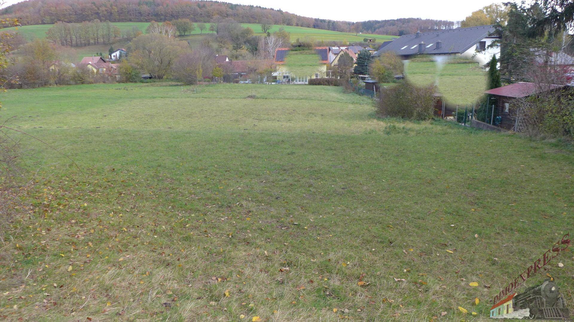 Weitläufiges grünes Grundstück mit Blick auf die umliegende Hügellandschaft und Häuser.