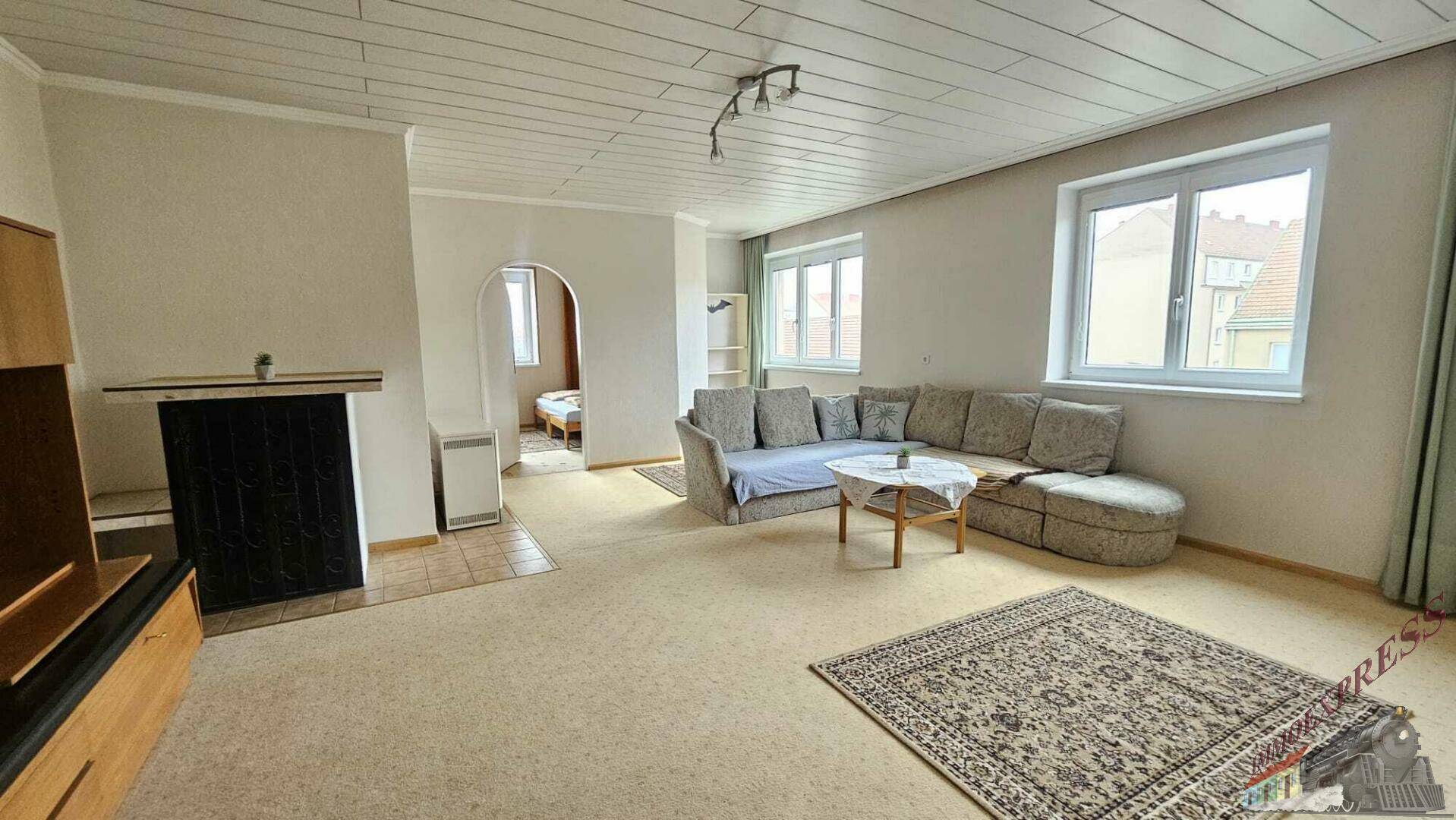 Gemütliches Wohnzimmer mit Kachelofen, bequemer Sitzecke und Blick in den Nebenraum.