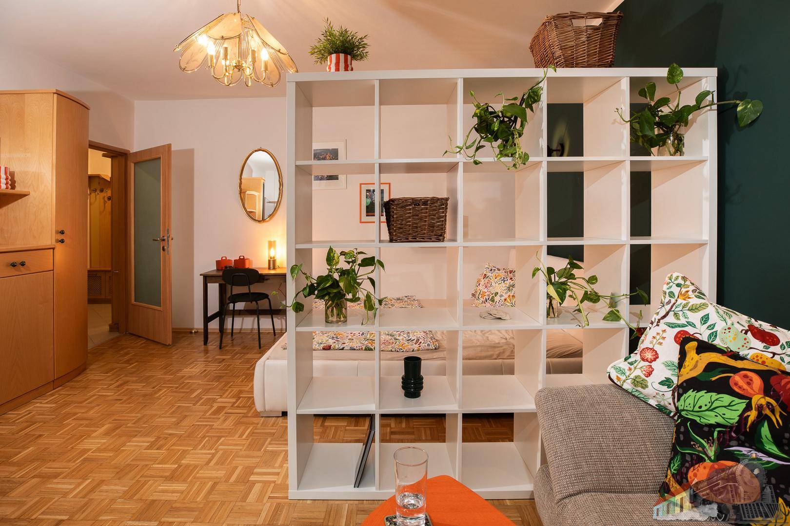 Offener Wohnbereich mit Bücherregal als Raumteiler und Zugang zum Schlafbereich.