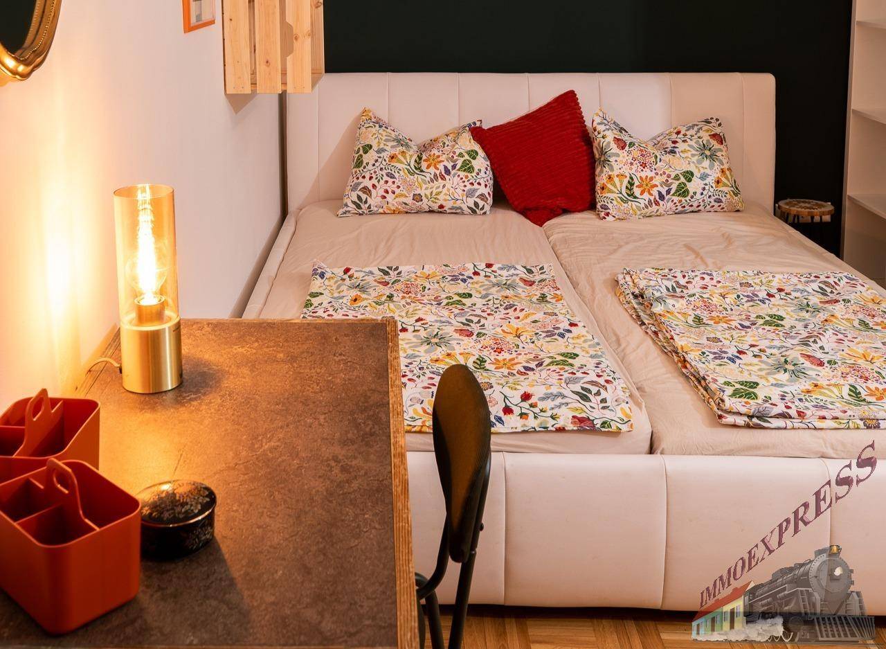 Gemütliches Schlafzimmer mit Doppelbett, floraler Bettwäsche und Nachttischlampe.