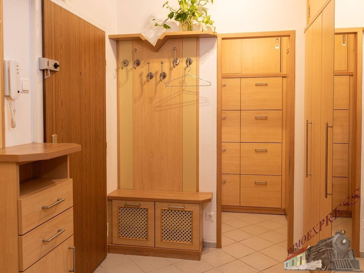 Eingangsbereich mit Garderobe, Schuhschrank und hellem Fliesenboden.
