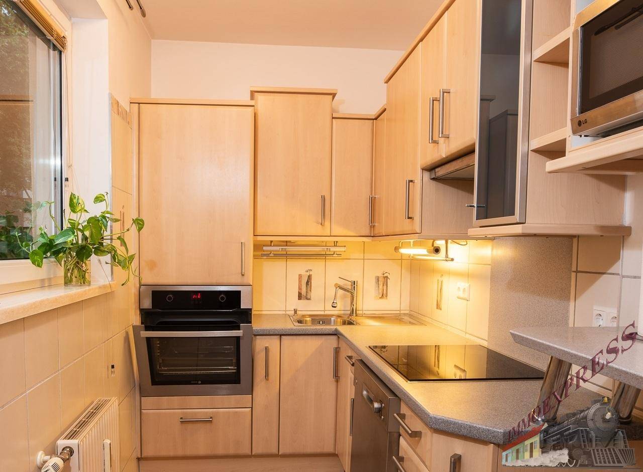 Funktionale Küche mit hellen Holzschränken, Einbaugeräten und Fenster für Tageslicht.