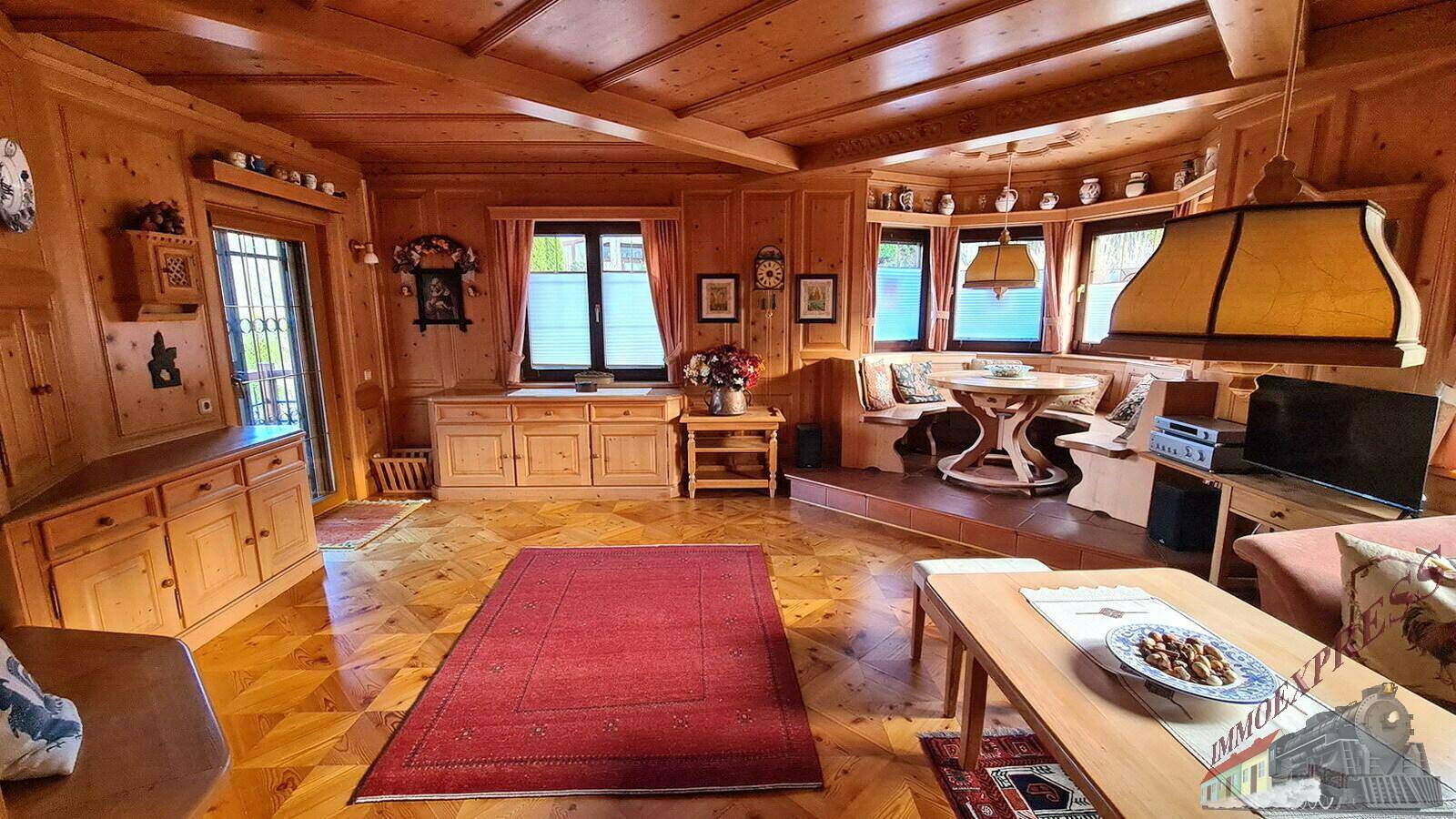 Gemütlicher Wohn- und Essbereich im alpinen Stil mit viel Holzvertäfelung und traditionellem Parkettboden.