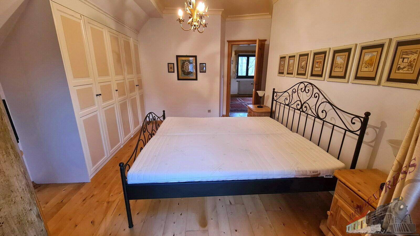 Geräumiges Schlafzimmer mit Holzboden, Einbauschränken und einem schmiedeeisernen Bettgestell.