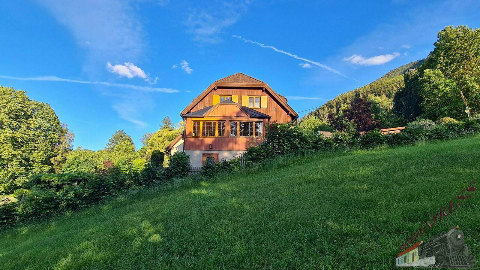 Das Haus liegt idyllisch auf einem grünen Hügel mit weitem Blick in die Natur.