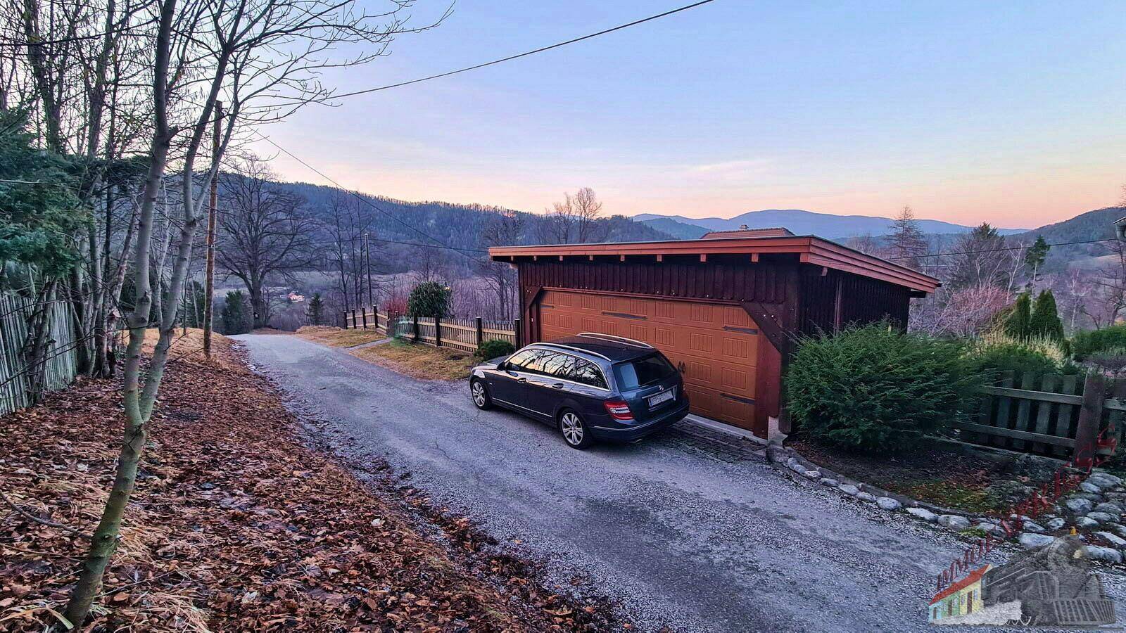 Auffahrt zu einem Haus mit einem geparkten Auto und malerischem Bergblick im Hintergrund.